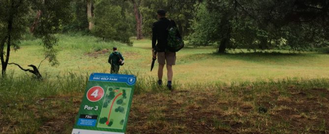 An image showing two men walking with umbrella and a disc golf park map