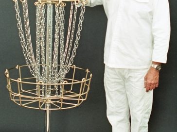 An image of man standing beside a disc golf target